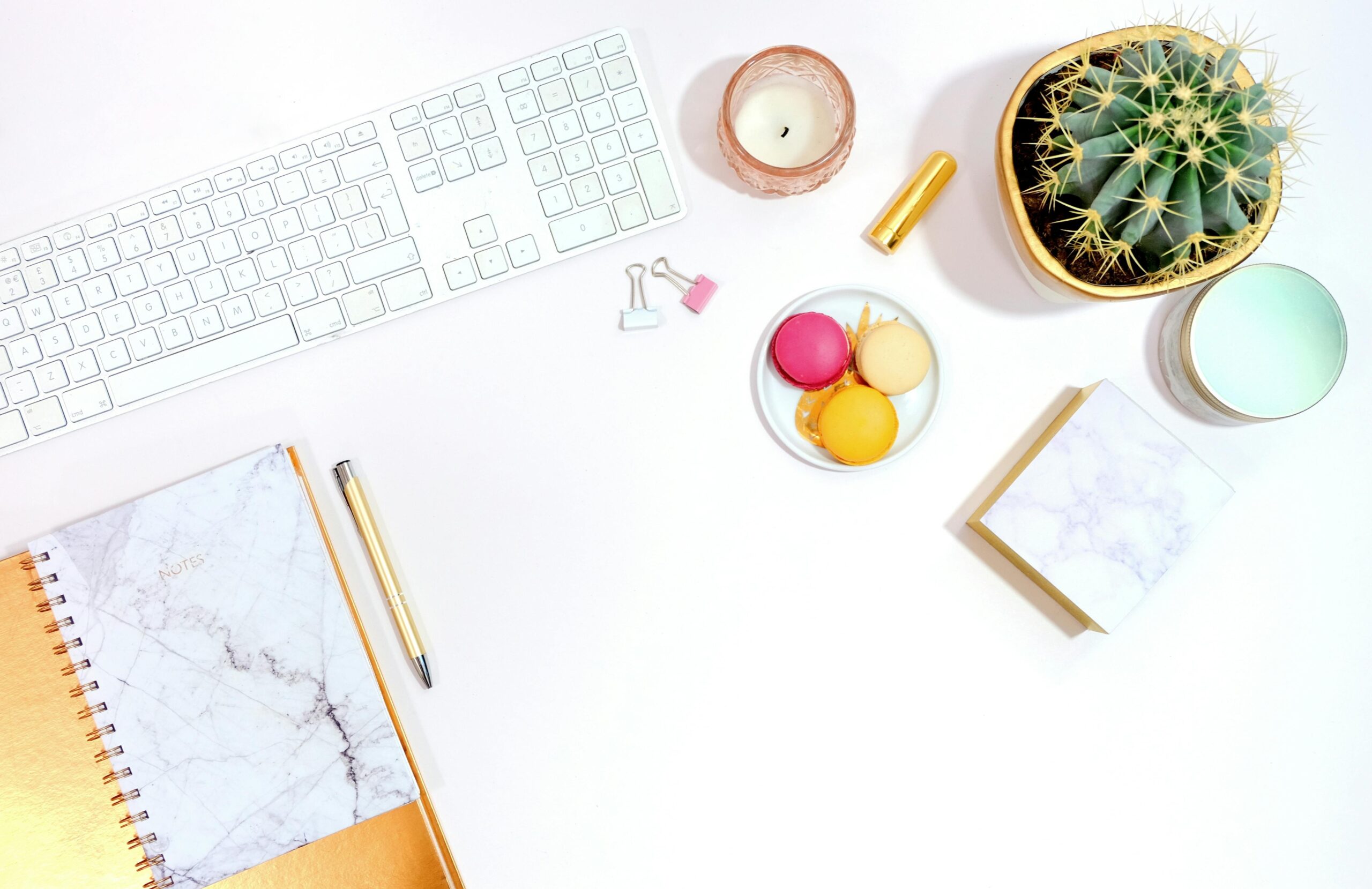 a white keyboard sitting next to a succulent and notebook